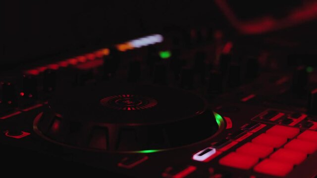 Dj playing music at the mixer controller in a night club