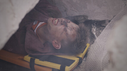 From above teen survivor lying on spinal board and yelling while being buried under concrete rubble...