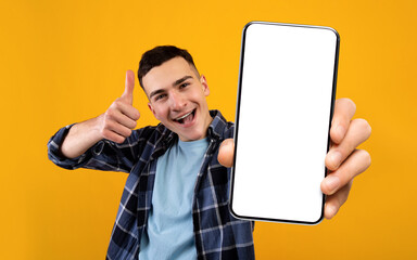Fototapeta na wymiar Mobile Application Ad. Excited Young Guy Showing Smartphone With Blank White Screen