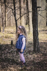Picture of an ethnic styled little girl with long hair in a headband playing in the forest