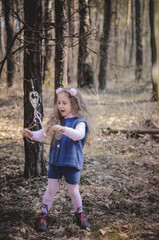 Picture of an ethnic styled little girl with long hair in a headband playing in the forest