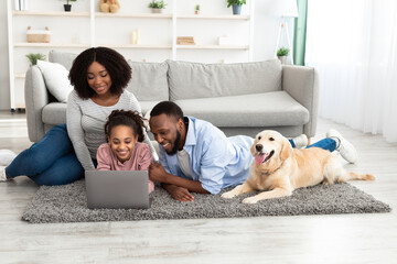 Black family at home using laptop relaxing with dog