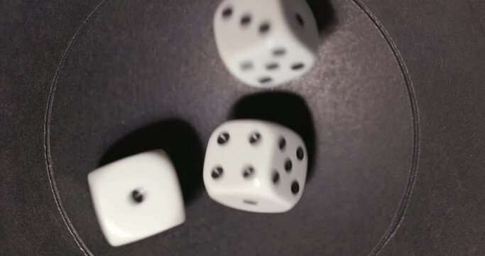 Plastic playing gambling dice rolling forever against dark background