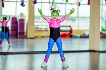 Fototapeta premium a small, beautiful girl,doing sports in the gym,in bright, colored sportswear