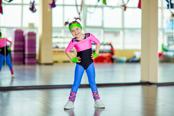 Fototapeta na wymiar a small, beautiful girl,doing sports in the gym,in bright, colored sportswear
