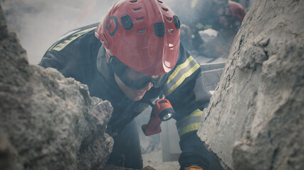 Tracking shot of man in protective uniform and hardhat calling coworkers and speaking to survivors...