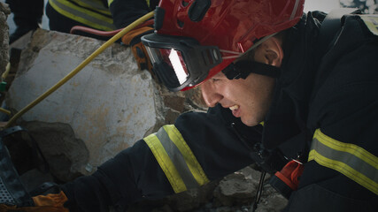 Men in protective uniform and hardhat inspecting remains of demolished building and speaking with...