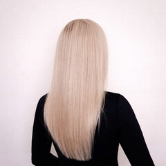 Female back with long, straight, healthy, blonde hair, on hairdressing salon background