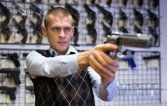 Man takes aim with a revolver when choosing in a gun store