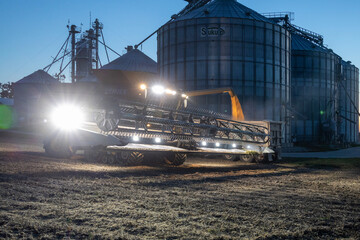 combine unloading harvest at dusk