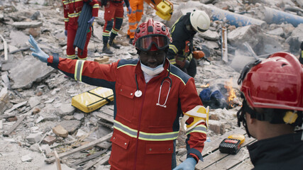 African American man in red uniform pointing away and talking with coworker during rescue mission...