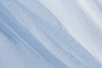 Beautiful winter background with snowy ground. Natural snow texture. Wind sculpted patterns on snow surface.