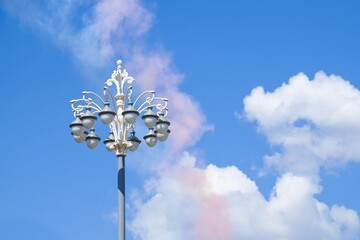 Beautiful old fashioned streetlight on the background of blue sky with fluffy clouds. Vintage street lamp post with many glass white lamps closeup in the Moscow city centre,Russia