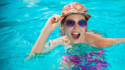 The girl swims in the pool and smiles.