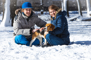 Fototapeta na wymiar Young family, couple in love on a winter walk with a beagle puppy.