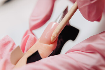 Manicure process. The master forms an artificial nail from a special gel using a bamboo stick.