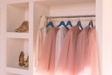 Pink women's dresses hang on wooden hangers