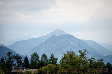 Fototapeta premium Panorama of the Hochstuhl mount, also called Veliki Stol vrh, between Slovenia and Austria, during a sunset, summit above clouds. It is a major mountain of the Julian Alps, in the karawanks chain