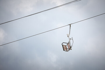 Selective blur on stopped ski lifts with a focus on an empty chair, not working in summer, in a ski resort, by slopes, in the middle of an alpine mountain...