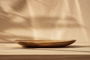 Bowl on wooden table and bright brown background with branch shadow on the wall. Mock up for...