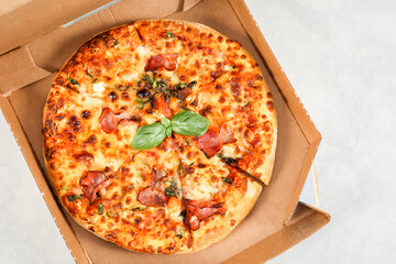 Round baked pizza in a craft box on a light gray