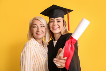 Happy female graduation student with her mother on color background