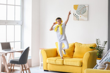 Cute little boy listening to music and dancing at home