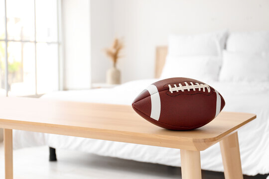 Rugby ball on wooden bench in light bedroom, closeup - Powered by Adobe