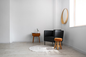 Black armchair, stool and table in light living room