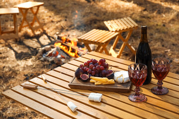 Red wine with tasty snacks on table in autumn forest