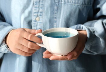 Woman with cup of butterfly pea flower tea, closeup