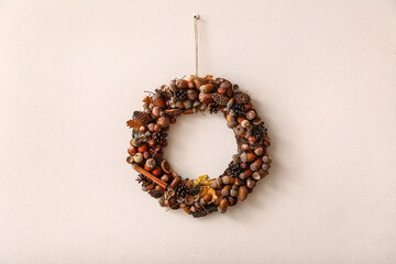 Beautiful acorn wreath on light wall © Pixel-Shot