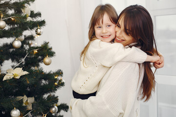 Mother with cute daughter standing near christmas tree