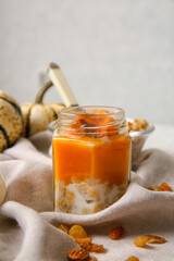 Jar of tasty oatmeal with pumpkin on light background
