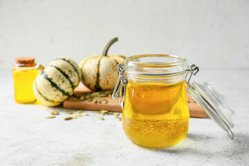 Jar with pumpkin seed oil on light background