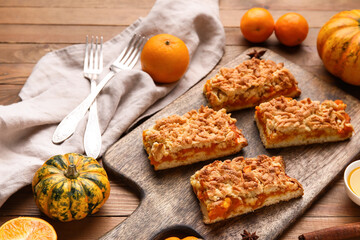 Board with pieces of tasty pumpkin pie on wooden background