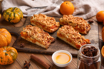 Board with pieces of tasty pumpkin pie on wooden background