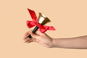 Woman holding Christmas bell with red ribbon on color background, closeup