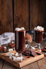 Glass cup of tasty hot chocolate with marshmallows on wooden background