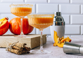 Autumn, Thanksgiving cocktails. Pumpkin margarita or Martini with cinnamon on stone table.