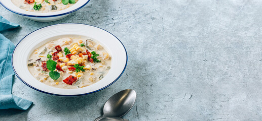 Creamy Corn, Zucchini and Bacon Chowder on blue stone background.