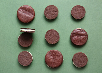 Tasty chocolate cookies with cream on green background