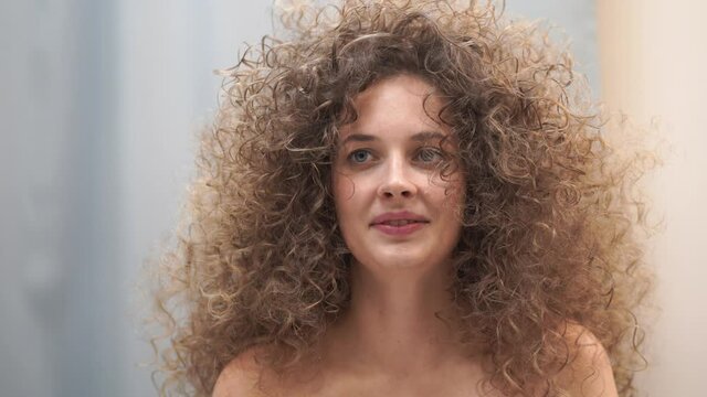 Close-up of a Caucasian woman with afro curls. She laughs and looks in different directions. High quality 4k footage