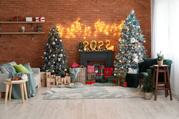 Interior of festive living room with Christmas trees, decorative mantelpiece and sofas