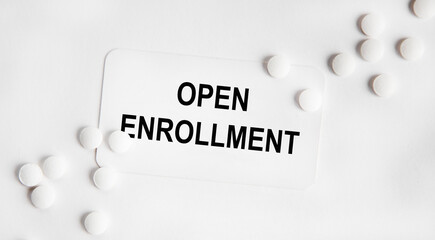 On the business card is the text of OPEN ENROLLMENT, next to neatly laid out white tablets.