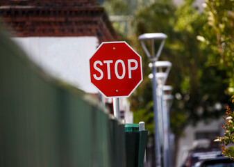 Stop sign behind a green fence in a city in Adelaide, South Australia