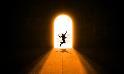 Businessman Jumping At Bright Door Light in A Dark Concrete Room. Silhouette of Happy Business Man Jumps At Shiny  Gate. Find The Way, Dream, Success and Achievement Concept 