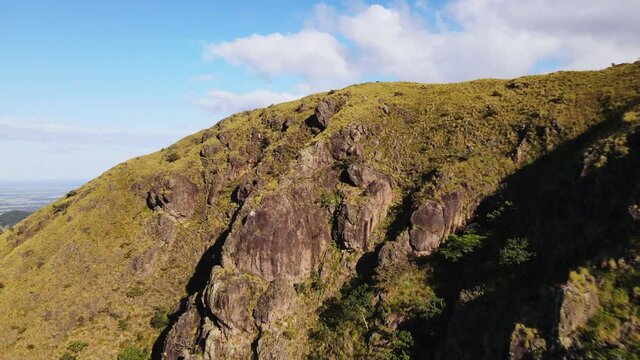 Drone approaching then flying over steep grassy cliff near Pelado peak in northern Costa Rica. Group of people sitting on the mountain ridge. 4k footage of central American tourist destination.