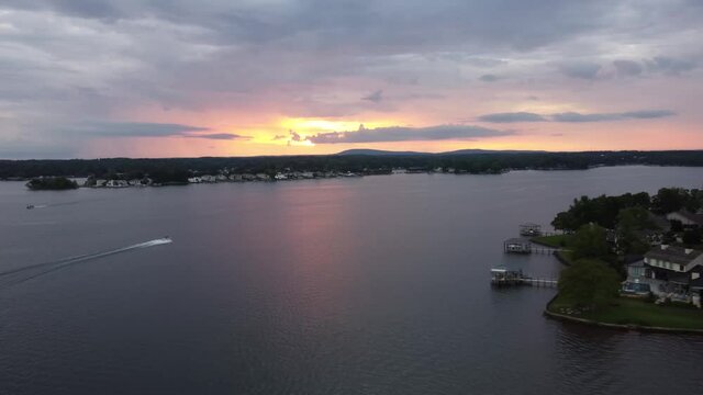 Drone shot of sunset on a lake with a couple boats skimming by.