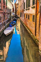 Fototapeta na wymiar Colorful small canal and bridge creating beautiful reflection in Venice, Italy.